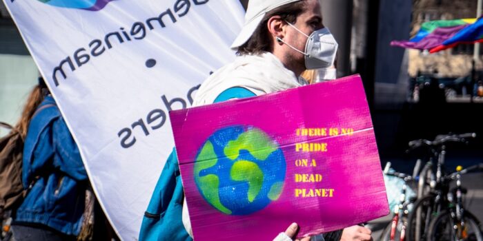 Mann trägt ein Plakat mit der Aufschrift 'There is no pride on a dead planet' während einer Demonstration.
